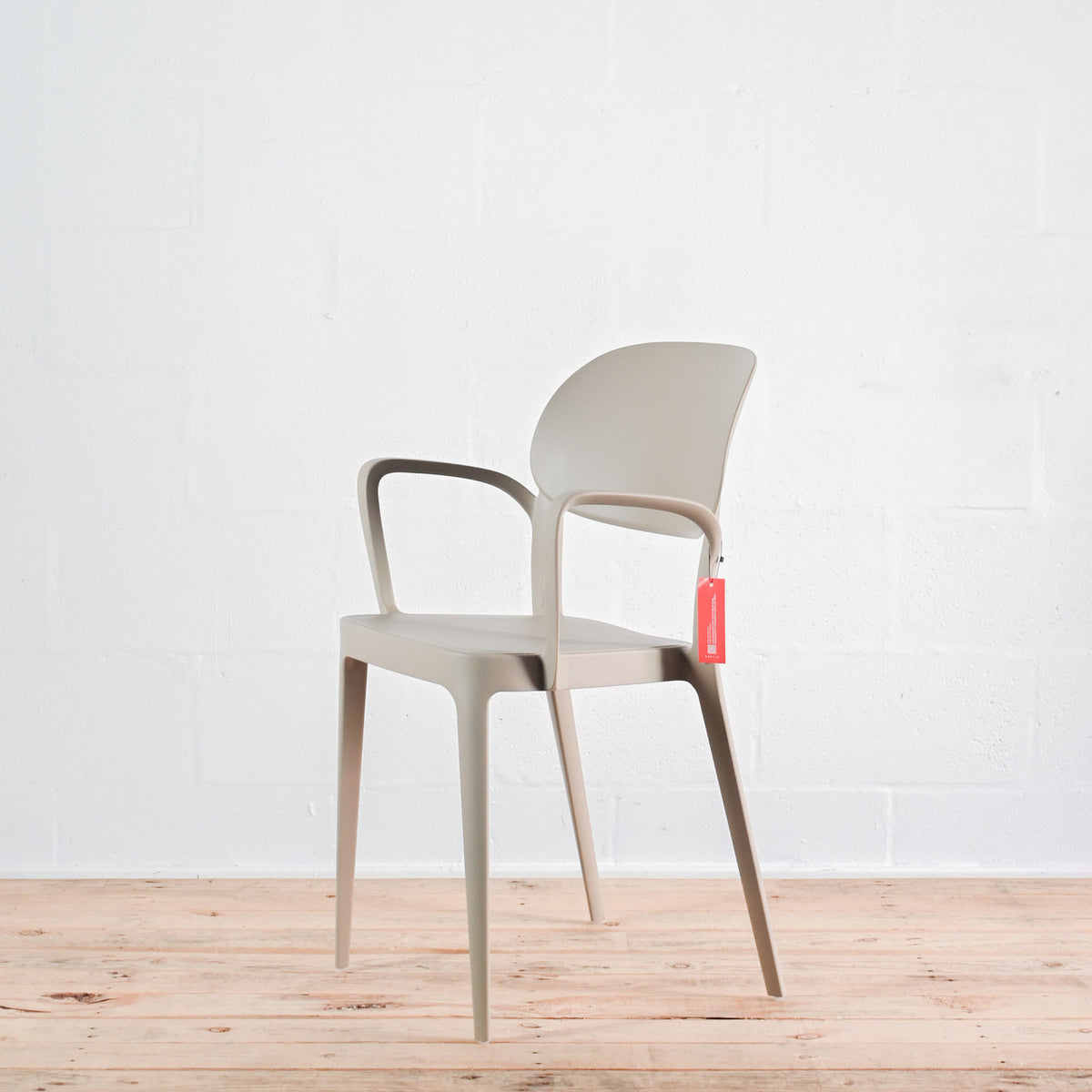 Side view of Alma Amy stacking chair with armrests in Sand